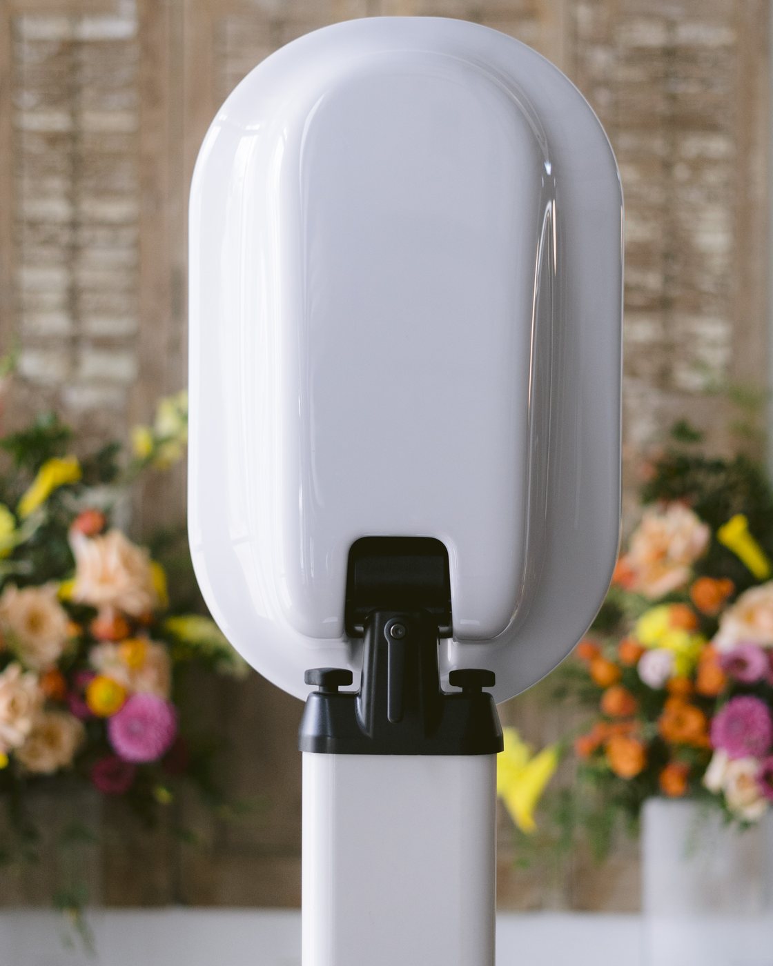 A June Light photo booth set up beside a wall of bright seasonal florals