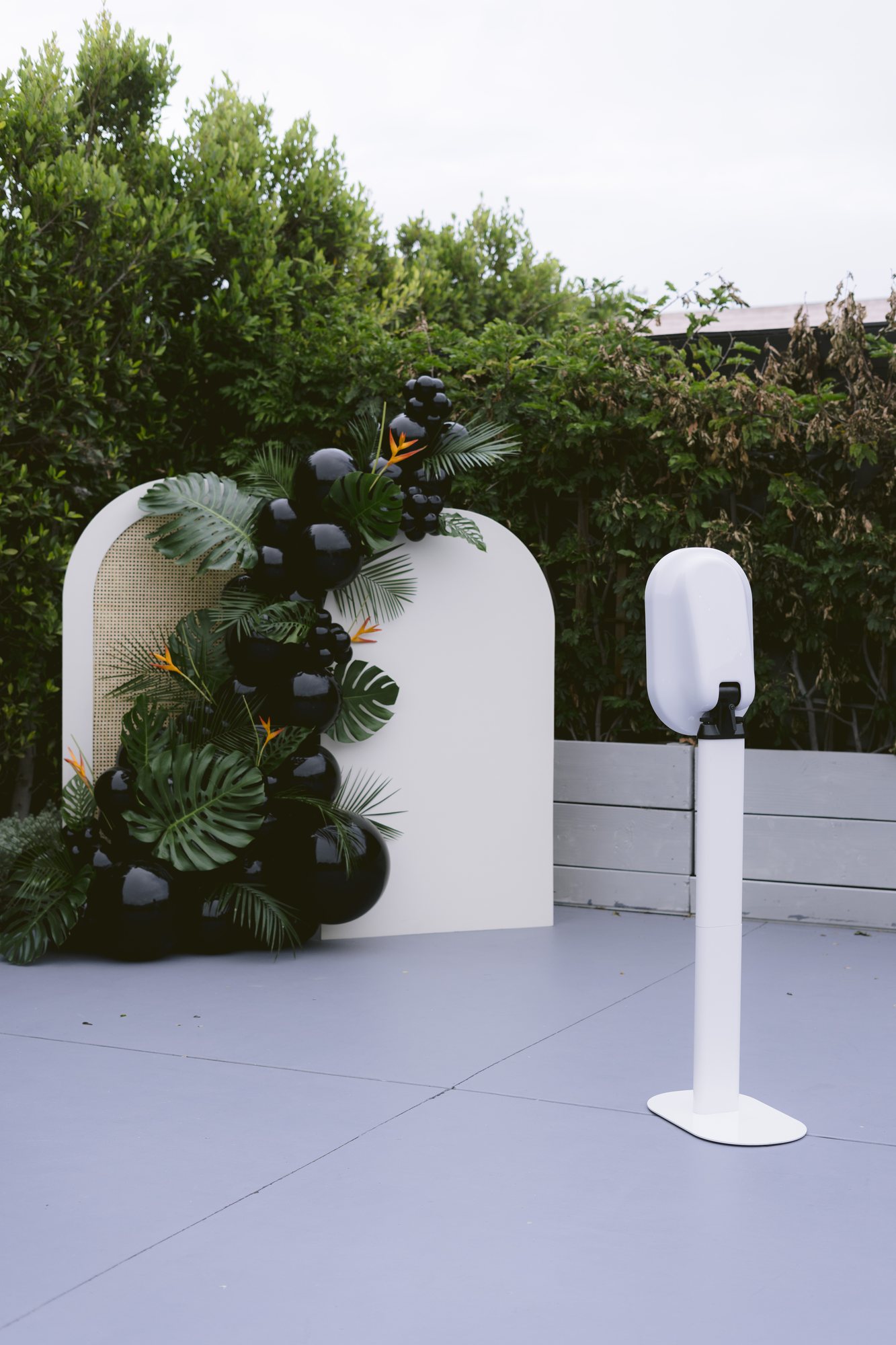 A June Light photo booth beside a floral arch on an outdoor terrace