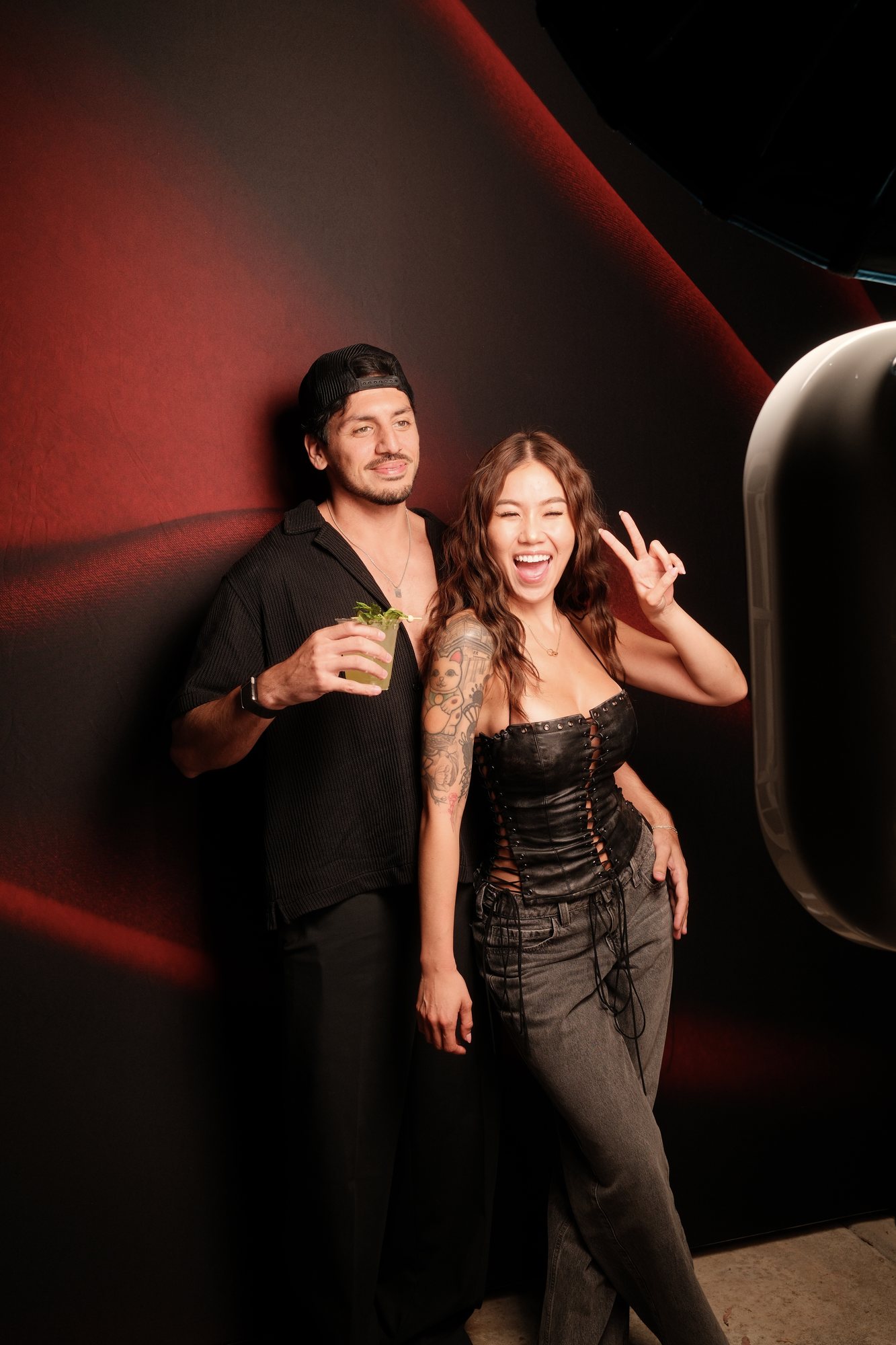 A couple photographed under studio lighting against a deep red backdrop