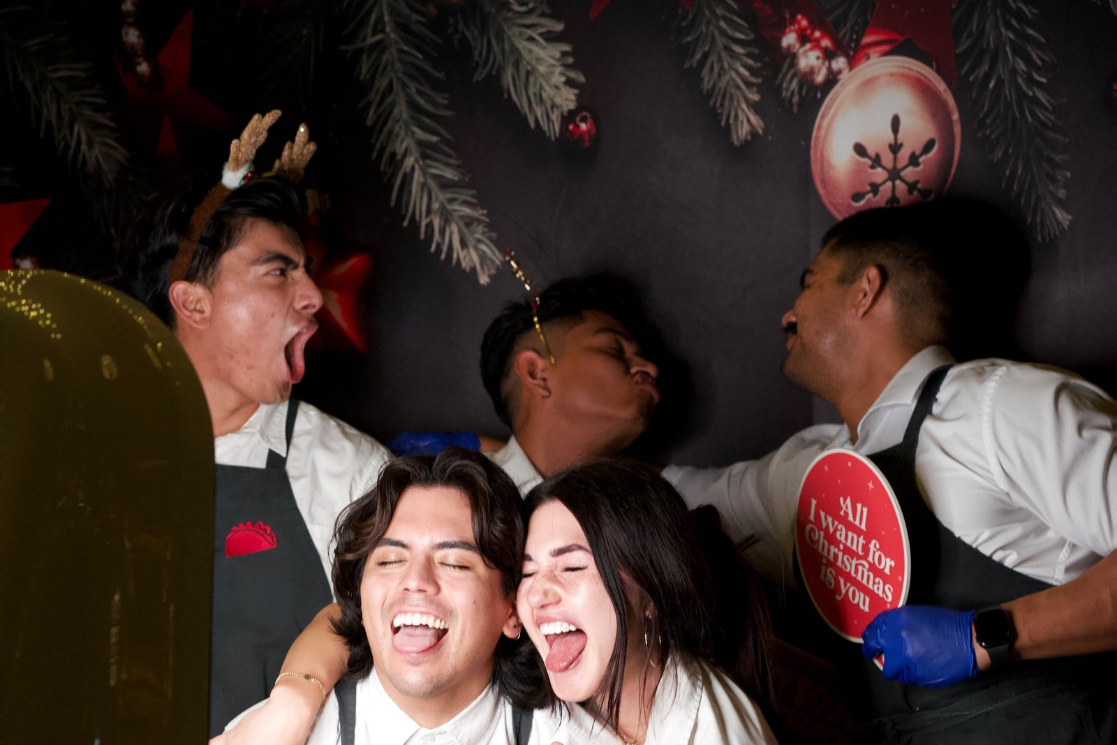 A team in aprons crowding into the booth at a company holiday party