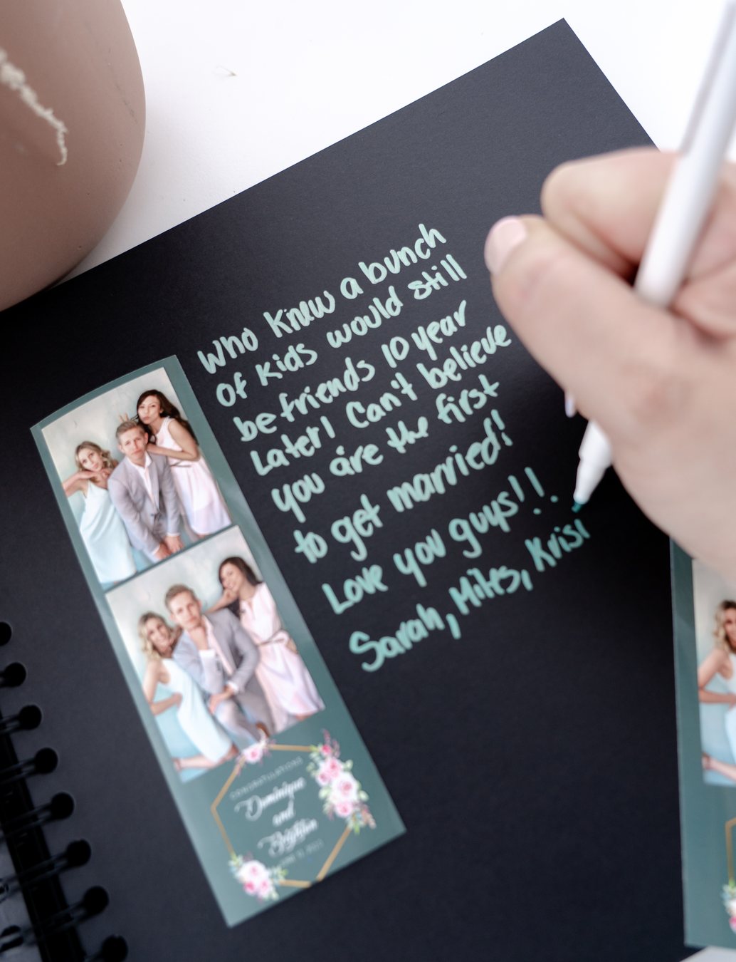 A guest writing a message in the keepsake guest book beside a printed photo strip