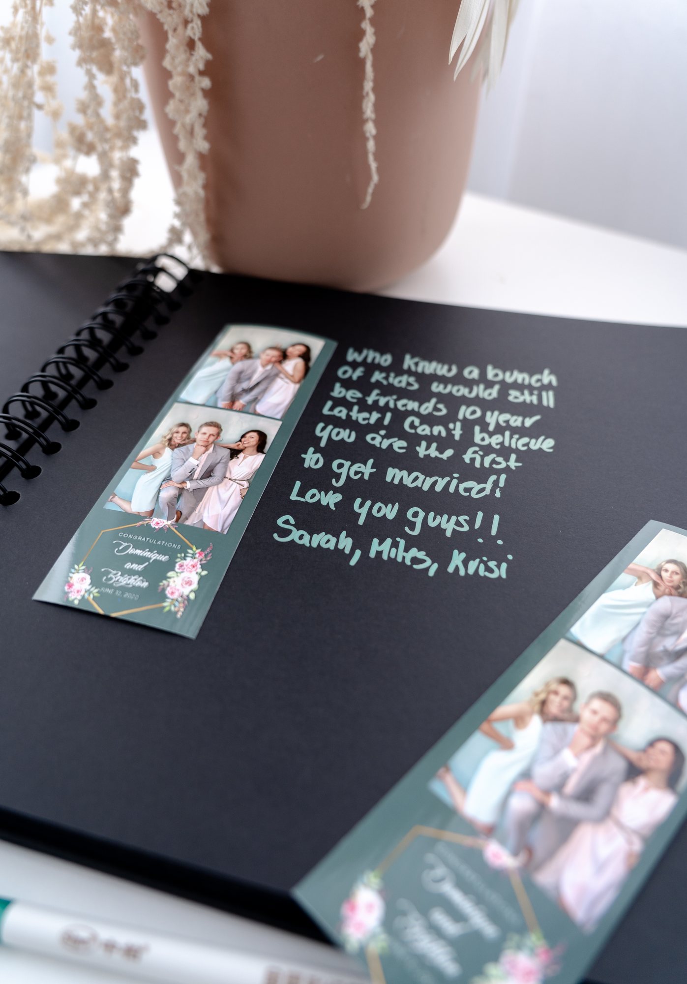 A black keepsake book holding photo strips from the night, tied with a ribbon