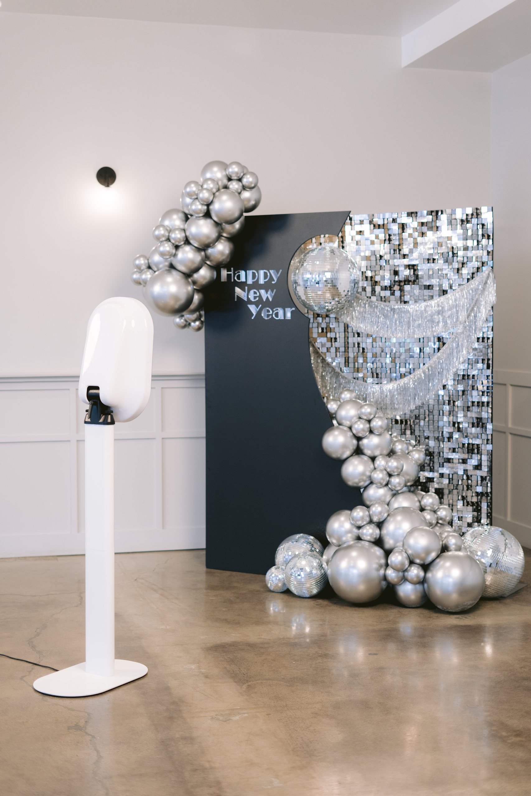 The booth beside a Happy New Year backdrop of silver balloons and mirrored spheres