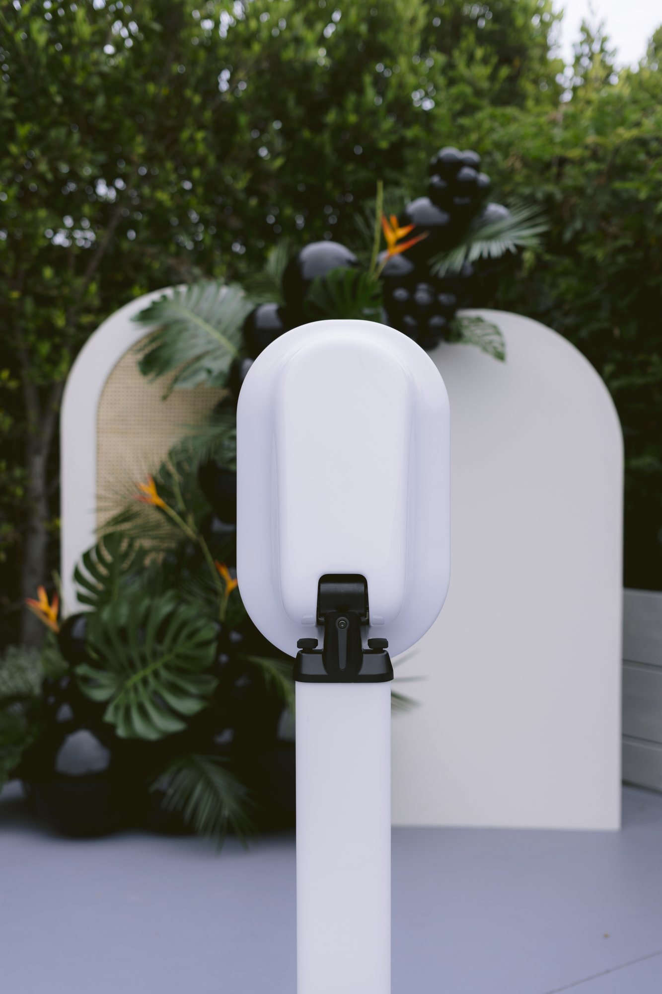 A June Light photo booth set up beside a leafy outdoor arch