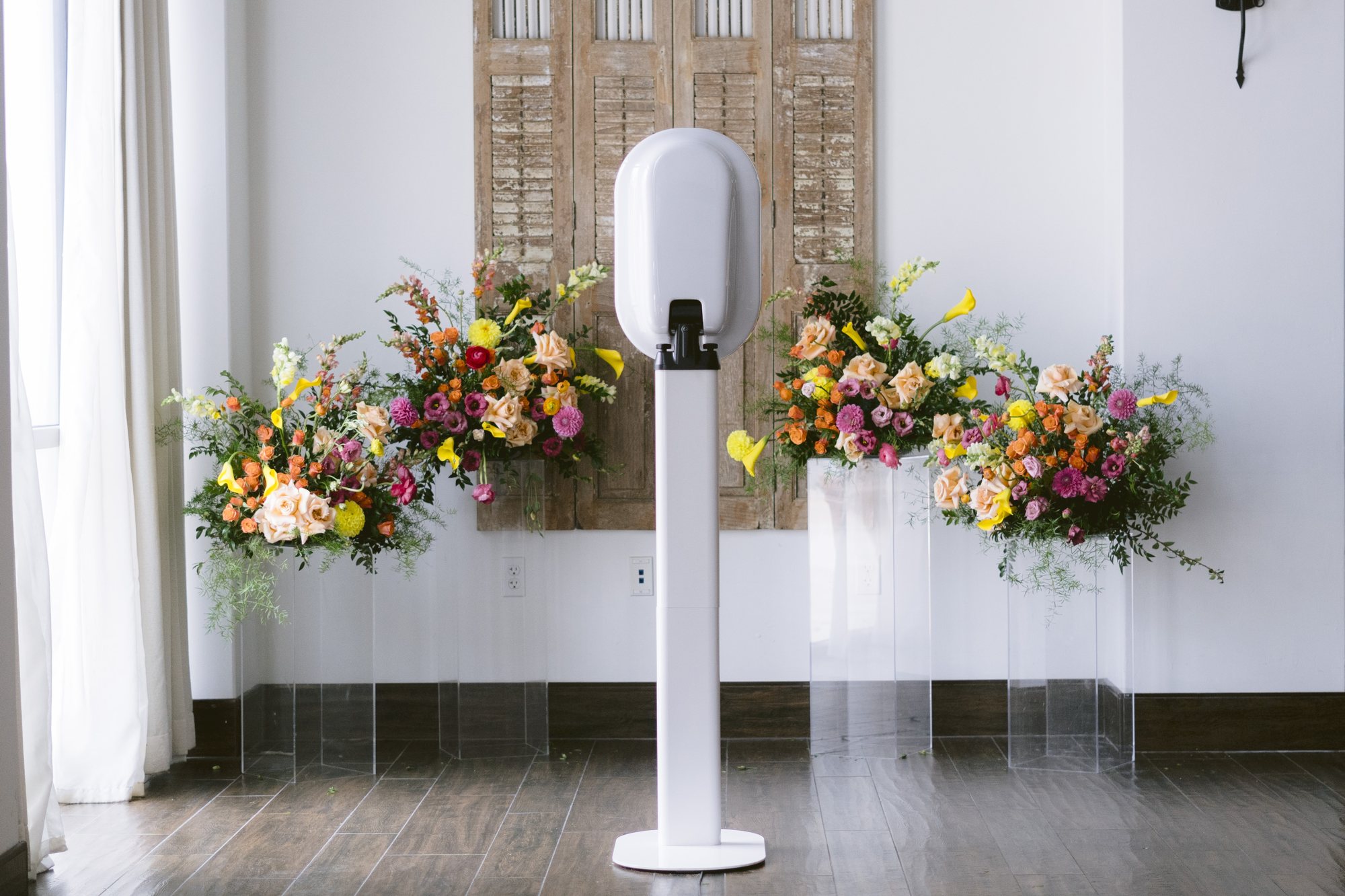 A photo booth framed by carved wood doors and a long spray of bright florals
