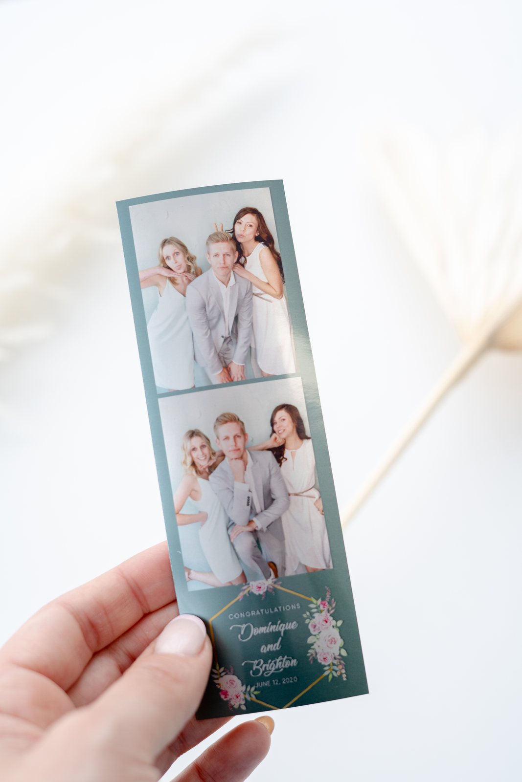 A hand holding a 2x6 photo strip printed at the booth